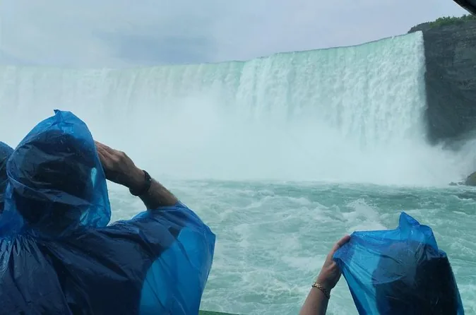 Pasajeros con ponchos azules frente a las cataratas